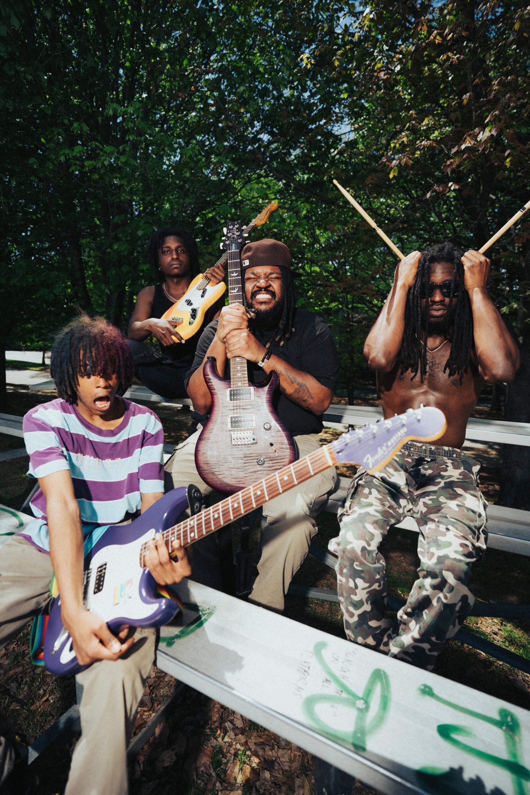 The Paradox — four band members posing with guitars and drumsticks on bleachers
